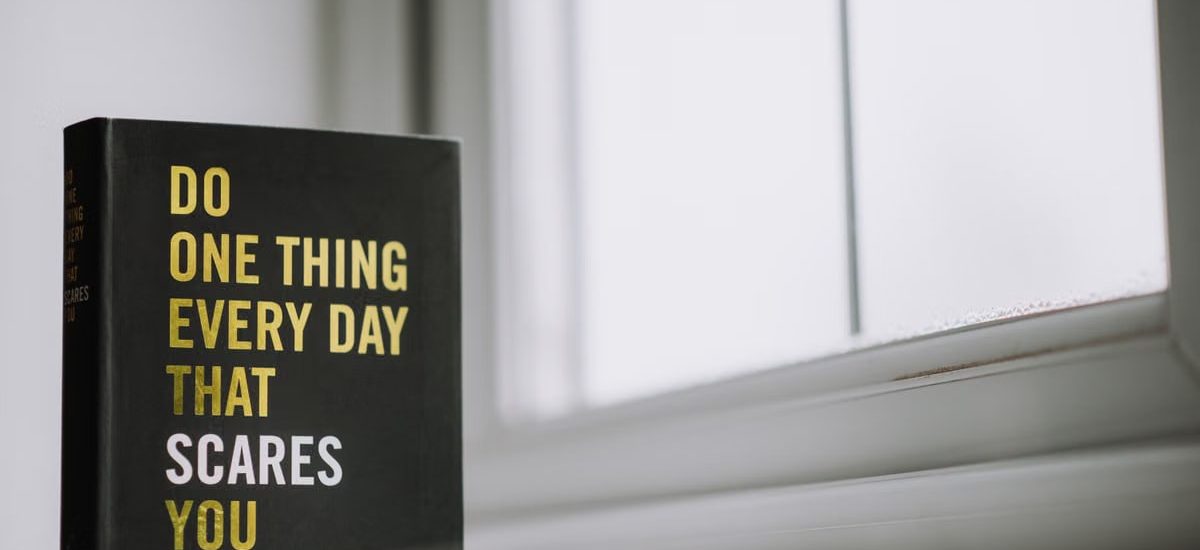 Rectangular shaped book with printed title on black hardcover on windowsill in house in daytime