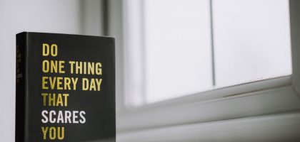 Rectangular shaped book with printed title on black hardcover on windowsill in house in daytime