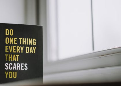 Rectangular shaped book with printed title on black hardcover on windowsill in house in daytime