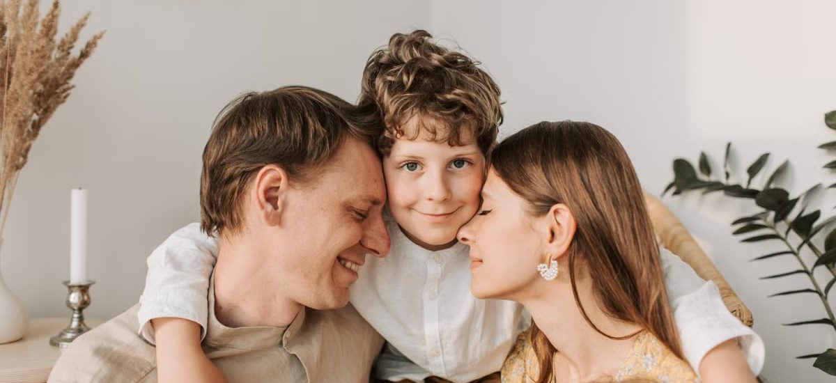 A joyful family moment with parents and their son embracing indoors.