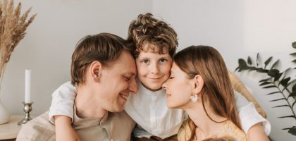 A joyful family moment with parents and their son embracing indoors.